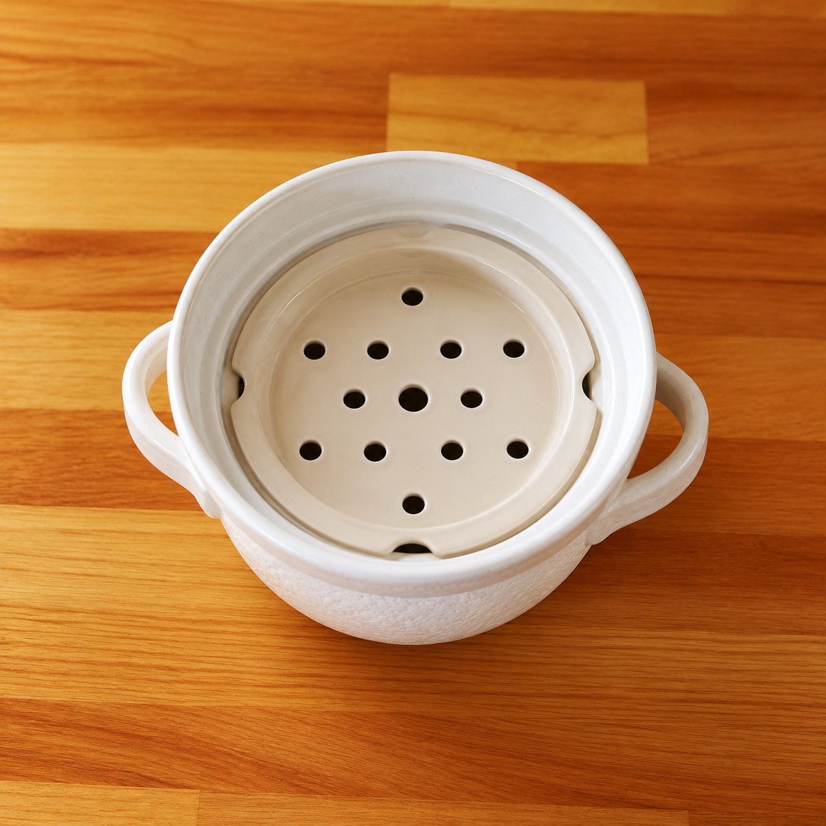 Top view of the white ceramic INAHO steamer tray with steam holes inside the 2-go donabe pot.